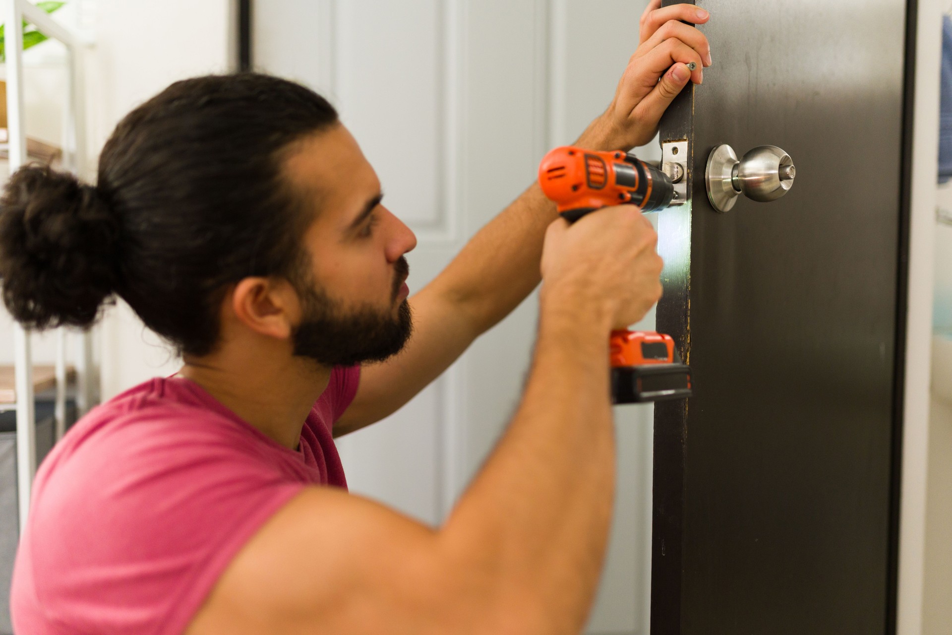 Handyman using cordless drill installing door lock